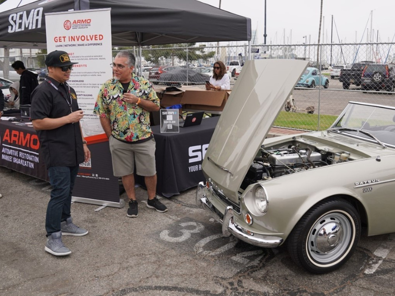 Attendees chatting next to display of cars