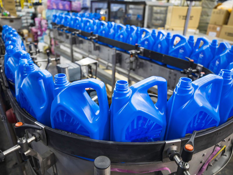 Plastic oil cartons on conveyor production line.